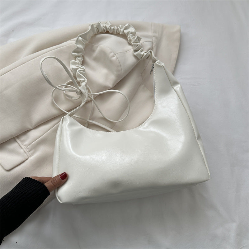 White handbag held by a hand on a white background