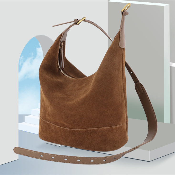 Brown suede handbag with a strap on a light background