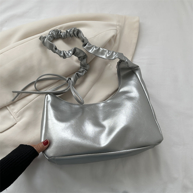 Silver handbag with ruched handle on a light background
